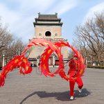 Hombre haciendo malabares con carioca delante de la Torre de la Campana de Pekín