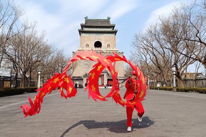 Hombre haciendo malabares con carioca delante de la Torre de la Campana de Pekín