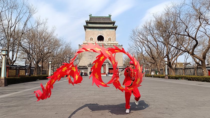 Hombre haciendo malabares con carioca delante de la Torre de la Campana de Pekín