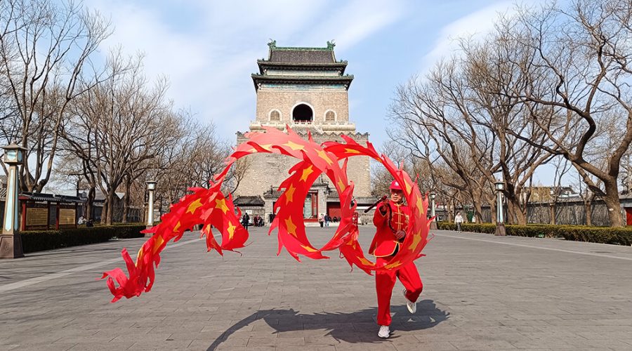 Hombre haciendo malabares con carioca delante de la Torre de la Campana de Pekín
