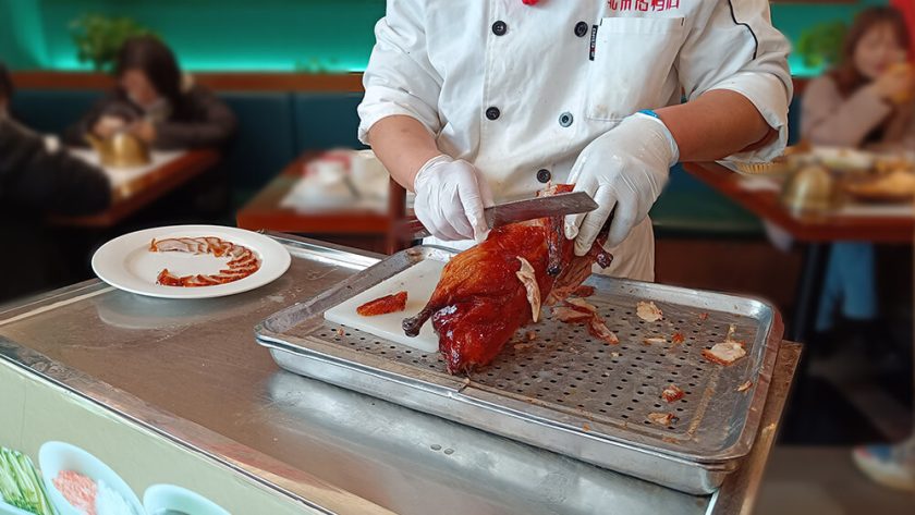 Cocinero sirviendo el pato laqueado en Nankín