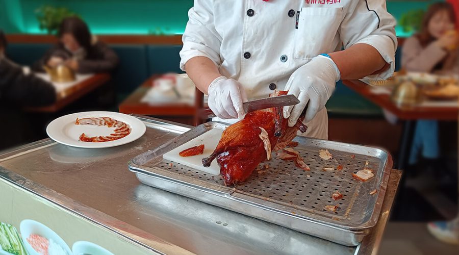 Cocinero sirviendo el pato laqueado en Nankín